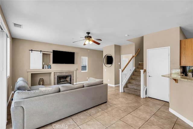 tiled living room with a tiled fireplace and ceiling fan