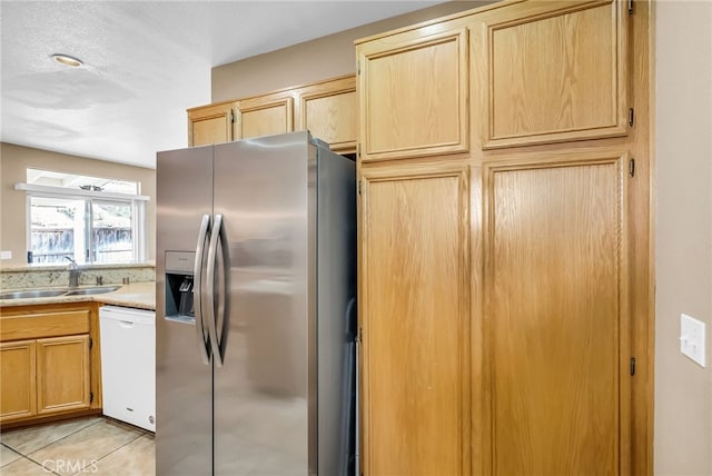 kitchen featuring sink, dishwasher, stainless steel refrigerator with ice dispenser, light tile patterned flooring, and light brown cabinetry