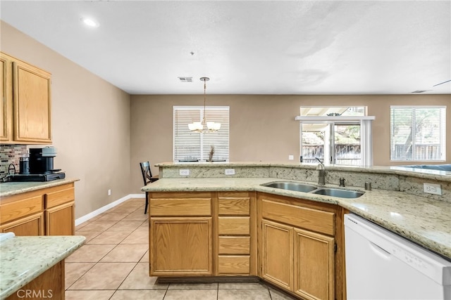 kitchen featuring pendant lighting, dishwasher, sink, light tile patterned floors, and light stone countertops