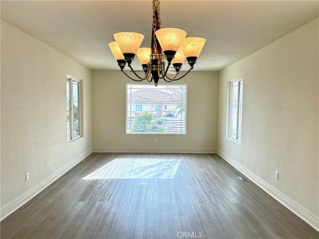 unfurnished dining area with a notable chandelier, dark hardwood / wood-style flooring, and a wealth of natural light