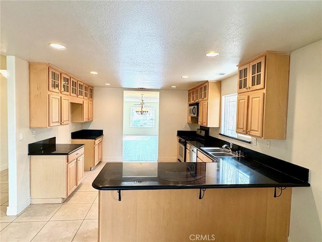 kitchen with sink, a kitchen bar, stainless steel appliances, light tile patterned flooring, and kitchen peninsula