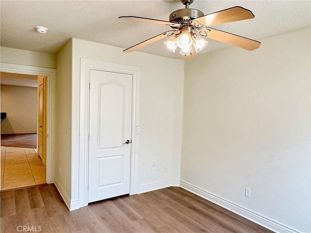 unfurnished bedroom with ceiling fan, a textured ceiling, and light wood-type flooring