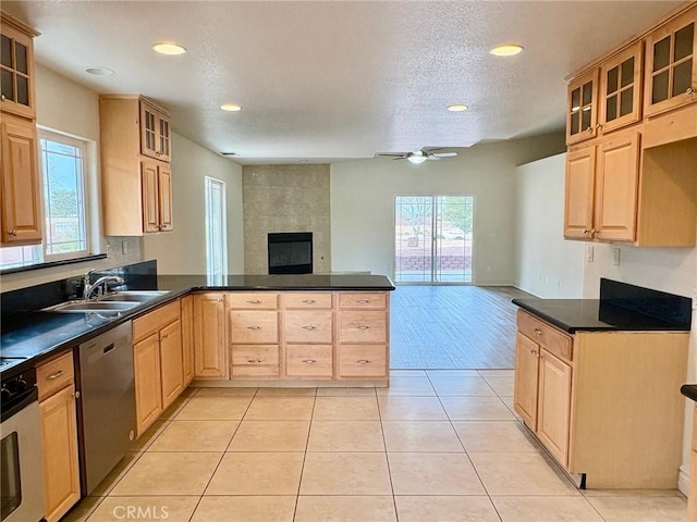 kitchen with sink, light tile patterned floors, stainless steel dishwasher, kitchen peninsula, and a healthy amount of sunlight