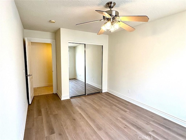 unfurnished bedroom featuring ceiling fan, light hardwood / wood-style flooring, a closet, and a textured ceiling