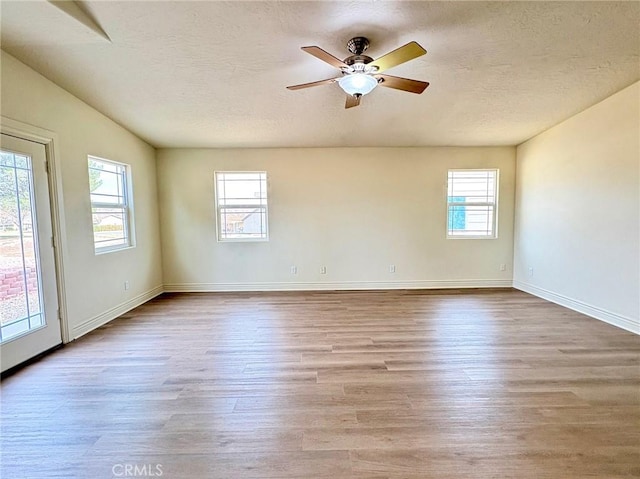 spare room featuring ceiling fan, plenty of natural light, a textured ceiling, and light wood-type flooring