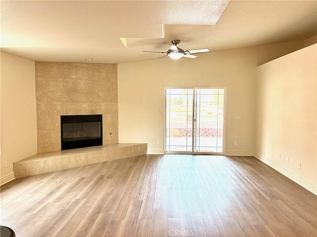 unfurnished living room with ceiling fan, a fireplace, and wood-type flooring