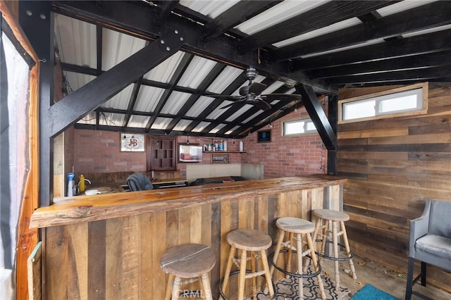 bar featuring butcher block counters, lofted ceiling with beams, ceiling fan, brick wall, and hardwood / wood-style floors