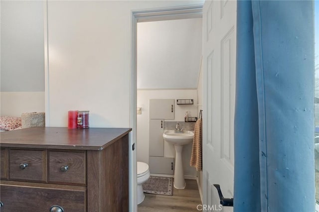 bathroom featuring lofted ceiling, sink, hardwood / wood-style floors, and toilet