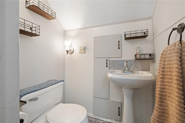 bathroom featuring ornamental molding, toilet, and backsplash