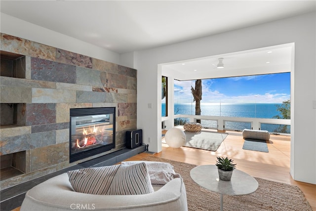 living room featuring a tile fireplace, a water view, and hardwood / wood-style floors