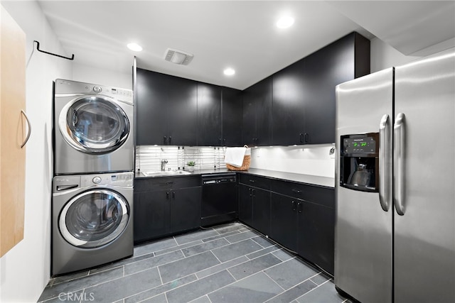 washroom featuring stacked washer / drying machine, sink, and dark tile patterned flooring