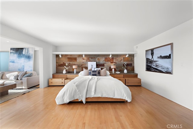 bedroom featuring hardwood / wood-style flooring and track lighting