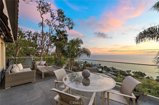 patio terrace at dusk featuring a water view and an outdoor living space