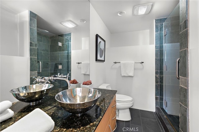 bathroom with tile patterned flooring, vanity, a shower with shower door, and toilet