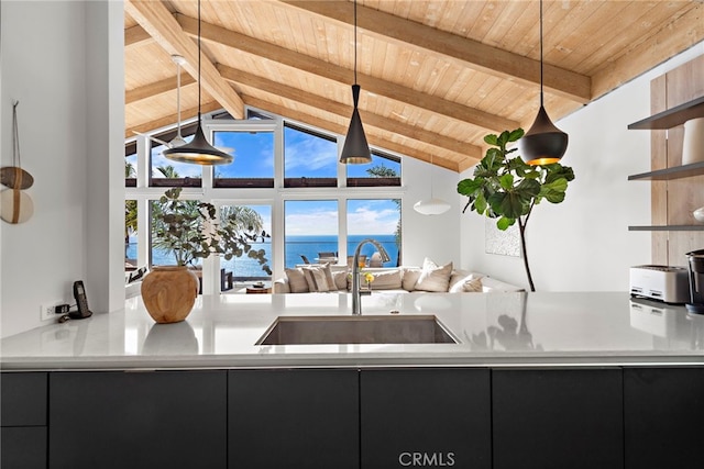 kitchen with sink, vaulted ceiling with beams, a water view, hanging light fixtures, and wooden ceiling