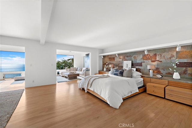 bedroom with access to outside, wood-type flooring, and a water view