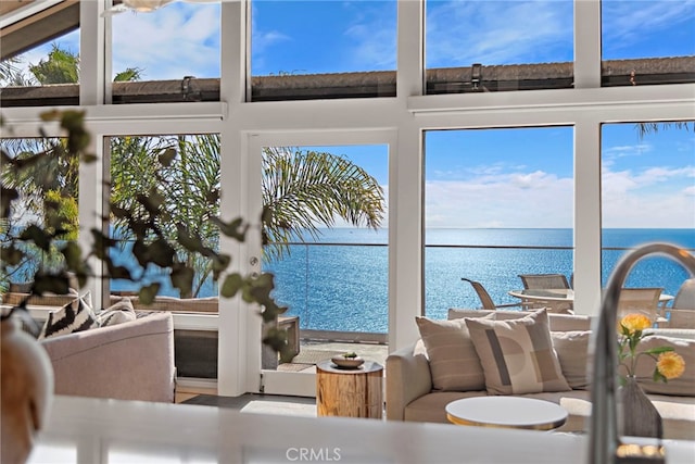 sunroom featuring a water view