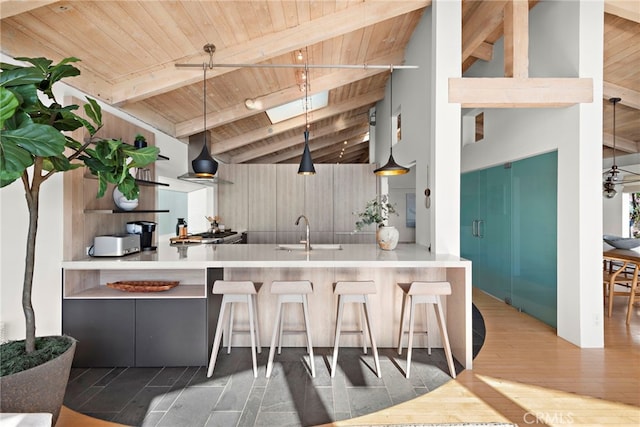 kitchen featuring lofted ceiling with skylight, pendant lighting, wood-type flooring, sink, and wood ceiling