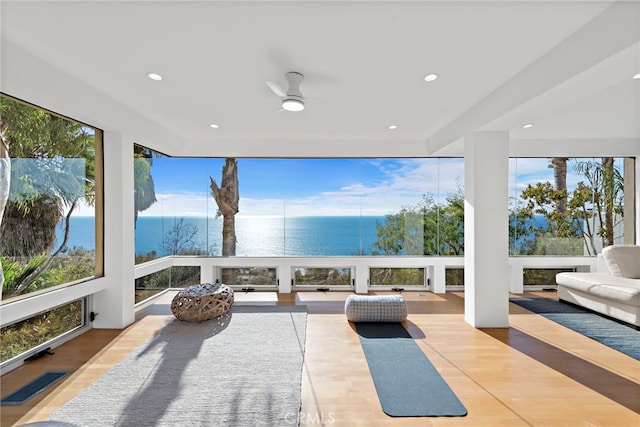 sunroom with a water view and ceiling fan