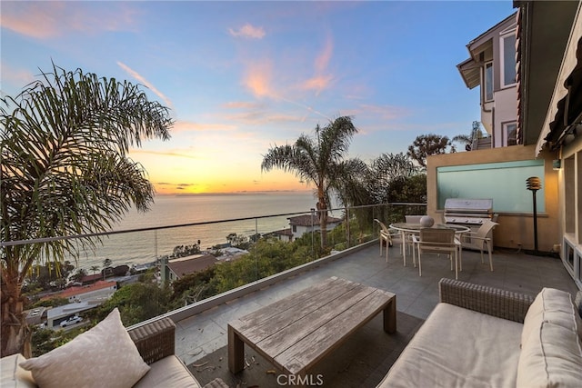 patio terrace at dusk with area for grilling, an outdoor hangout area, and a water view