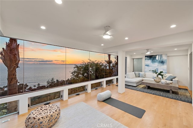 exercise area featuring hardwood / wood-style floors, ceiling fan, and a water view