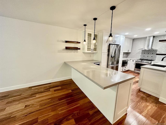 kitchen with wall chimney exhaust hood, decorative light fixtures, kitchen peninsula, stainless steel appliances, and white cabinets