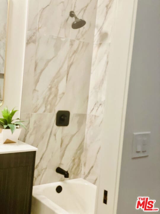 bathroom featuring tiled shower / bath and vanity