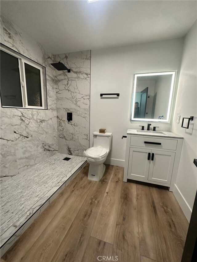 bathroom with vanity, wood-type flooring, toilet, and a tile shower