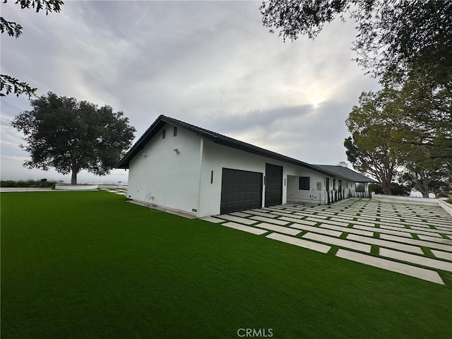 back of property featuring a garage and a yard