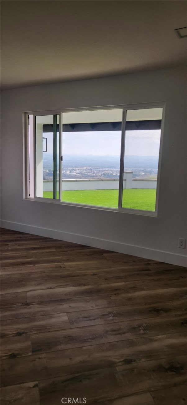 spare room featuring a water view, a healthy amount of sunlight, and dark wood-type flooring