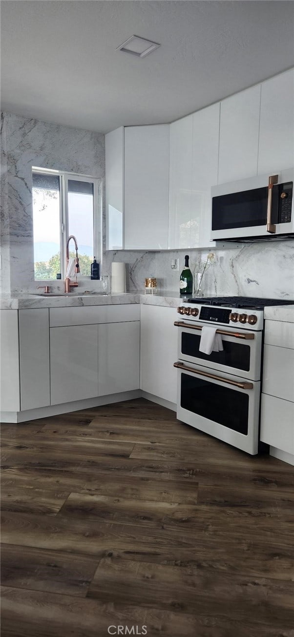 kitchen featuring white cabinetry, white appliances, dark wood-type flooring, and backsplash