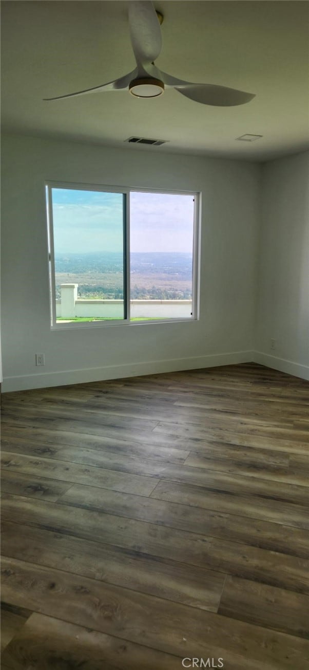 empty room featuring dark wood-type flooring and ceiling fan