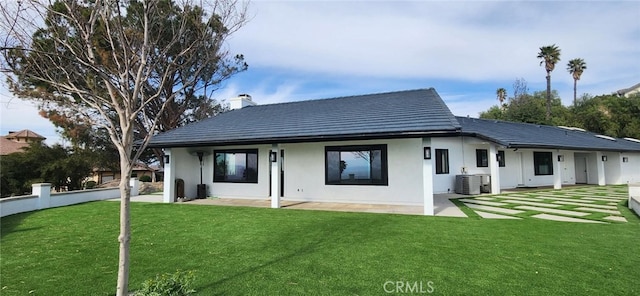 back of property featuring a lawn, central air condition unit, and a patio area