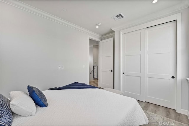 bedroom featuring crown molding, light wood-type flooring, and a closet