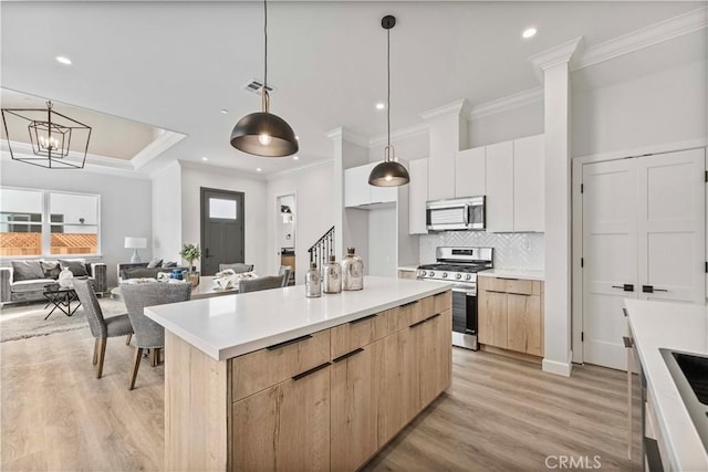 kitchen featuring pendant lighting, appliances with stainless steel finishes, light brown cabinetry, and white cabinets