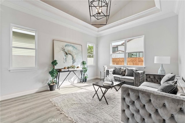 living room with crown molding, a chandelier, and light hardwood / wood-style floors