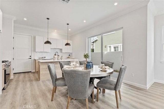 dining room with ornamental molding and light hardwood / wood-style flooring