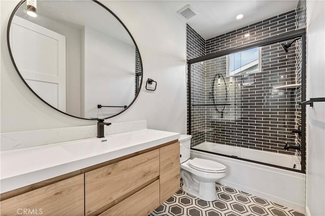 full bathroom featuring enclosed tub / shower combo, vanity, and toilet