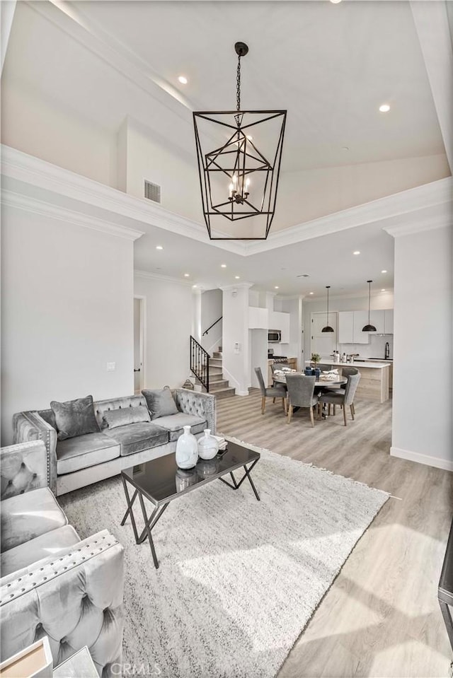 living room featuring crown molding, a notable chandelier, and light wood-type flooring