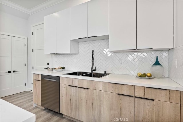 kitchen featuring sink, crown molding, light hardwood / wood-style flooring, stainless steel dishwasher, and white cabinets