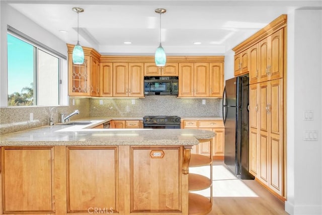 kitchen featuring sink, black appliances, a kitchen bar, decorative backsplash, and kitchen peninsula