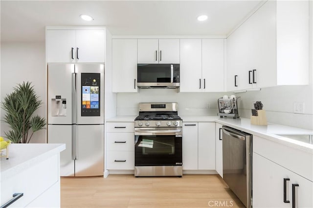 kitchen with stainless steel appliances, white cabinetry, and light wood-type flooring