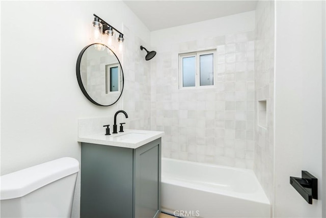 full bathroom with tiled shower / bath, vanity, and toilet