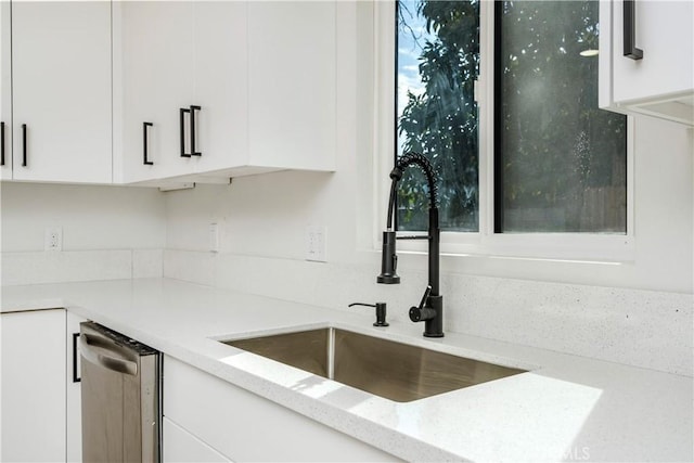 kitchen with white cabinetry, light stone countertops, sink, and stainless steel dishwasher