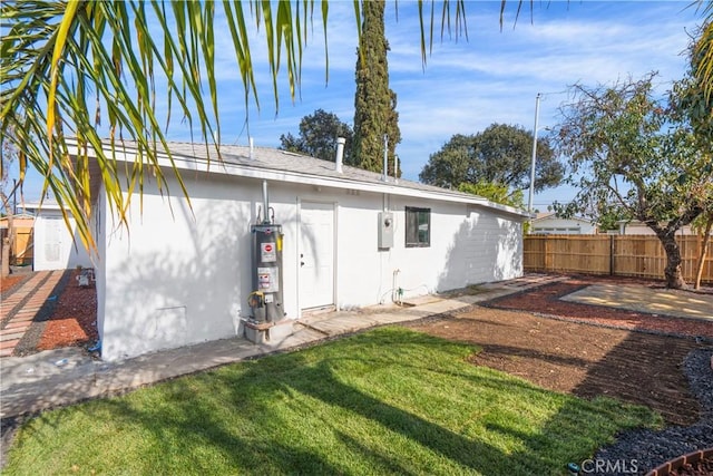 rear view of house with water heater and a yard