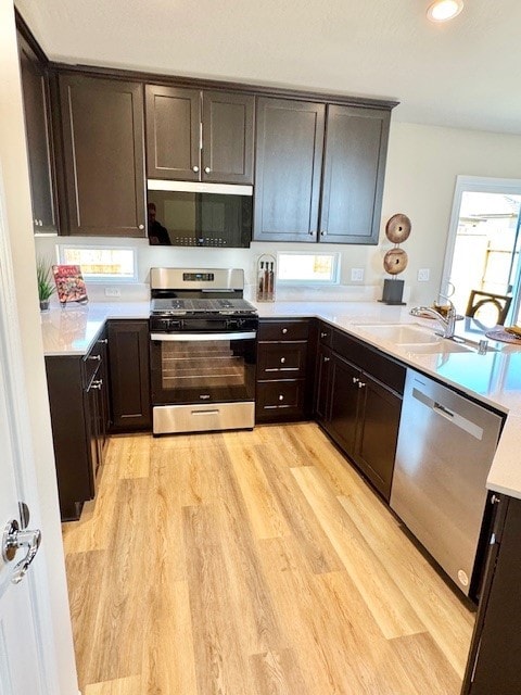 kitchen with light wood-type flooring, sink, dark brown cabinets, and appliances with stainless steel finishes