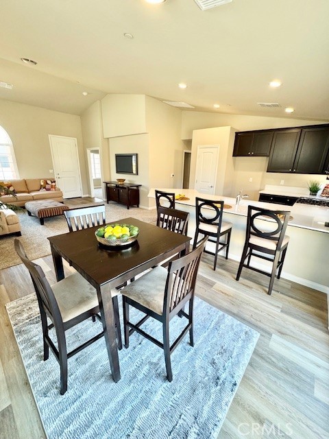 dining space with plenty of natural light, light hardwood / wood-style floors, and vaulted ceiling