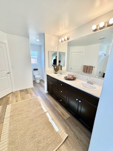 bathroom with hardwood / wood-style flooring, vanity, a textured ceiling, and toilet