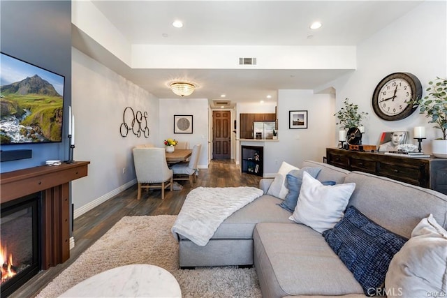 living area with dark wood finished floors, recessed lighting, visible vents, a glass covered fireplace, and baseboards