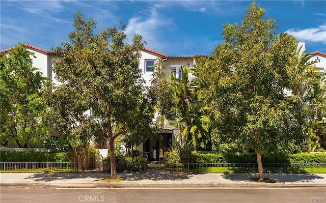 view of front of property featuring a fenced front yard, a tiled roof, and stucco siding